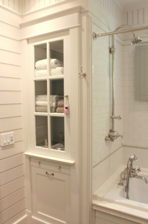 Smart bathroom storage makes use of a narrow space with great molding and a glass-front door.