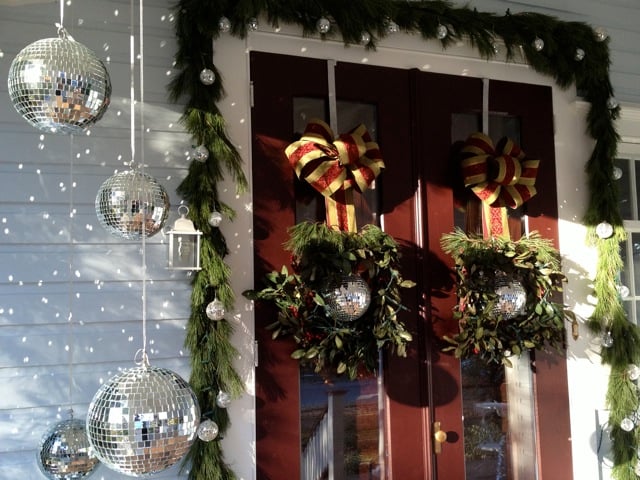 Fun, easy, sparkly Christmas decorations. ornaments. Using mirror balls as front porch decorations. Evergreen garland around front doors. DIY large bow. How to make a bow. Hanging wreaths from ribbon. Unusual Christmas decorations. Decorating your front door and porch.